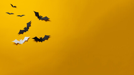 Halloween decorations concept. Black paper bats on orange background. Banner, copy space.