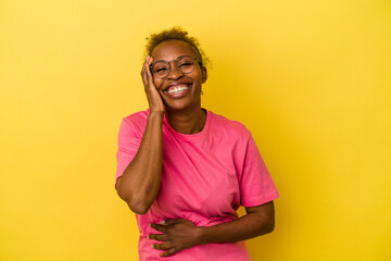 Young african american woman isolated on yellow background laughs happily and has fun keeping hands...