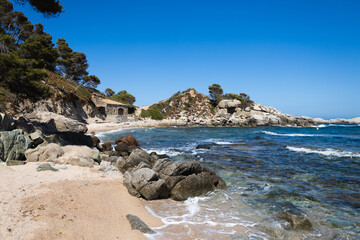 Obraz premium Cala estreta in Palamos, Costa Brava, Spain, sandy beach with sea and rocky mountain