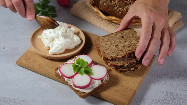 Woman preparing sandwiches and spreads soft cheese on the bread, 4k video