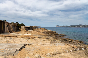 Boathouses on the rocky yellow beach in Ibiza, Spain