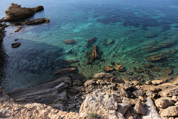 Cala roja in Ibiza, rocky seashore with crystal blue water, Spain