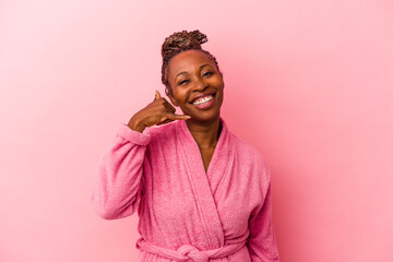 Young african american woman wearing pink bathrobe isolated on pink background showing a mobile phone call gesture with fingers.