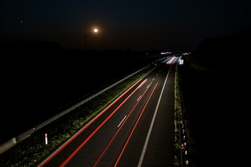 Late night traffic on the motorway with a full moon in the background