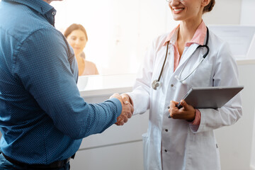 Doctor and patient greeting each other and shaking hands at front desk of doctor's office