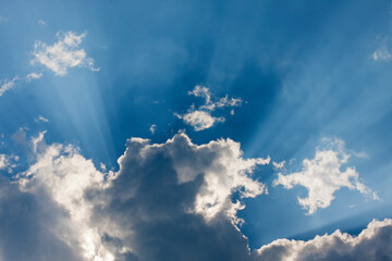 Beautiful blue sky with sunbeams and clouds. Sun rays.