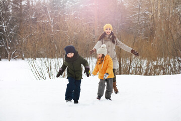 Happy family playing and laughing in winter outdoors in the snow. City park winter day.