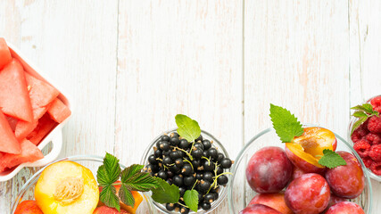 Variety of ripe summer fruits and berries on wooden background