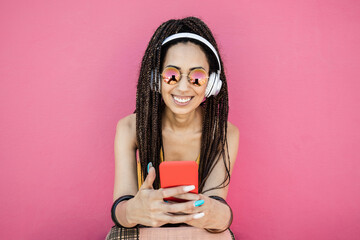 Happy bohemian influencer woman listening playlist music with pink background - Focus on face