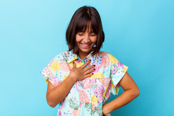 Young mixed race woman isolated on blue background laughing keeping hands on heart, concept of happiness.