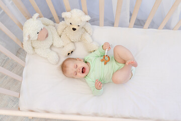 a crying baby in a crib with a teether in the bedroom