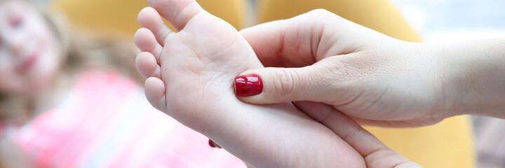 Podiatrist holding child leg in massage parlor closeup