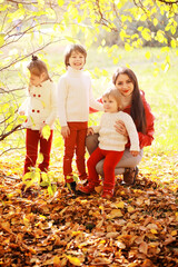Fototapeta premium Young family on a walk in the autumn park on a sunny day. Happiness to be together.