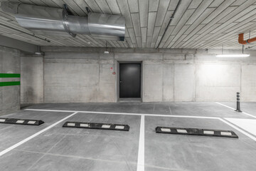 Empty public underground parking lot or garage interior with concrete stripe painted columns and...