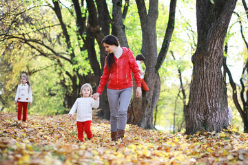 Children for a walk in the autumn park. Leaf fall in the park. Family. Fall. Happiness.