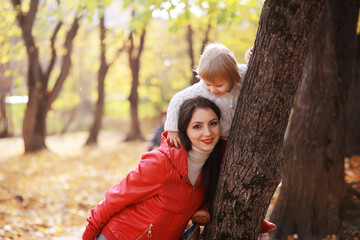 Young family on a walk in the autumn park on a sunny day. Happiness to be together.