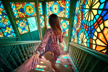 Follow me and traveling together. Girl with short dress and round straw bag holds boyfriends hand...
