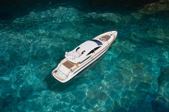 Super yacht on clear water near the rocks, top view. A huge white super Mega yacht on blue water in Italy. © Berg