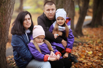 Fototapeta na wymiar Young family on a walk in the autumn park on a sunny day. Happiness to be together.