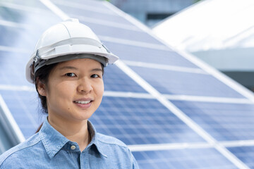 Close-up portrait with copy space of a confident Asian woman wearing white safety hard hat and blue...