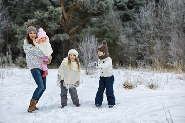 Happy family playing and laughing in winter outdoors in the snow. City park winter day.