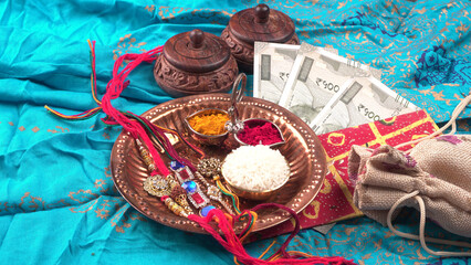 Indian festival: Raksha Bandhan background with an elegant Rakhi, Rice Grains and Kumkum. A traditional Indian wrist band which is a symbol of love between Brothers and Sisters.
