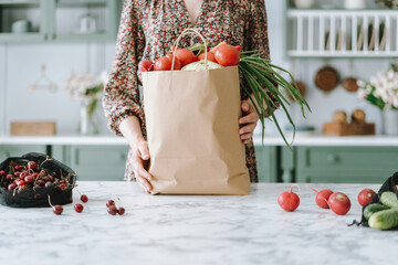 Woman holding paper grocery bag with vegetables