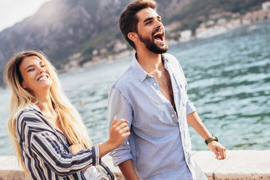 Happy casual couple holding hands and walking near the sea - Powered by Adobe
