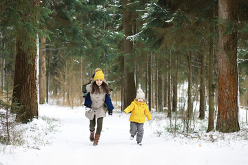 Happy family playing and laughing in winter outdoors in the snow. City park winter day.