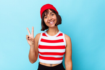 Young mixed race woman isolated on blue background joyful and carefree showing a peace symbol with fingers.