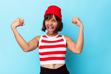 Fototapeta na wymiar Young mixed race woman isolated on blue background showing strength gesture with arms, symbol of feminine power