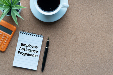 EMPLOYEE ASSISTANCE PROGRAMME text with calculator,notepad, keyboard, decorative plant, coffee cups and fountain pen on wooden background. Technology, Business and copy space concept..