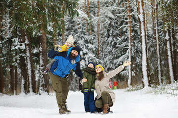 Happy family playing and laughing in winter outdoors in the snow. City park winter day.