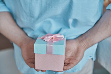 Close-up of man holding gift box behind his back