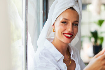 Beautiful happy female portrait. Woman wearing red lipstick and turban towel on head while relaxing...