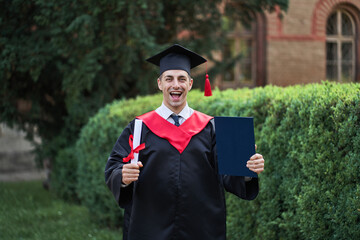 Emotional caucasian graduate in graduation robe and diploma in university campus