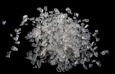 Crystals of white sea salt isolated on black background.