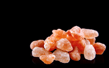 Crystals of pink Himalayan salt close-up on a black background.