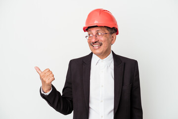 Middle aged indian architect man isolated on white background points with thumb finger away, laughing and carefree.
