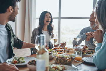 Happy multi-generation family communicating and smiling while having dinner together