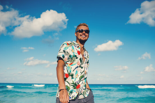 Fototapeta Young tourist man wearing hawaiian shirt at the sea or the ocean background. Travel vacation holiday. Man walking at the sea, enjoy tropical season