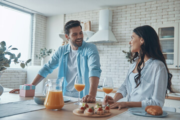 Beautiful young couple enjoying breakfast together while spending time in the domestic kitchen