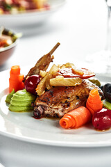 Grilled quail with vegetable stew, light plate table with white tablecloth and cutlery