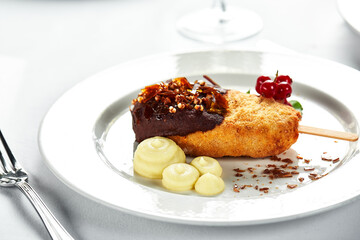 Chicken Kiev with mashed potatoes and a sprig of red currants on a bright plate, white background copy Space, the original supply of Kiev cutlets