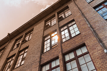 The facade of the wall of a brick house with windows reflecting sunlight