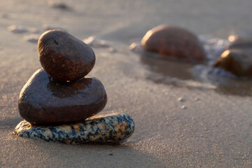 smooth dark stones lie on wet sand by the sea. Sunny day on the Baltic Sea. Close-up.