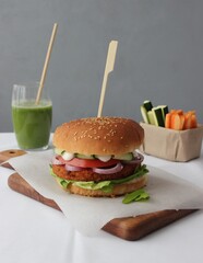 Healthy vegan burger served with a smuthie an vegetables