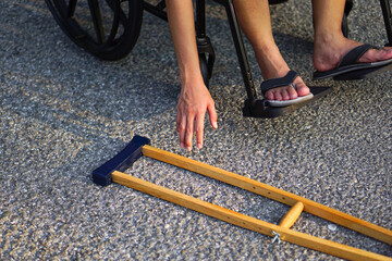 The patient sat on a wheelchair, reached his hand or bowed down, picked up a crutch on the floor....