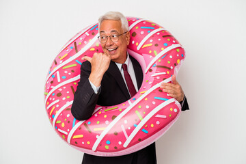 Senior american man holding inflatable donut isolated on white background points with thumb finger...