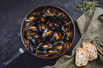 Traditional barbecue Italian blue mussel in tomato red wine sauce with baguette bread as top view...